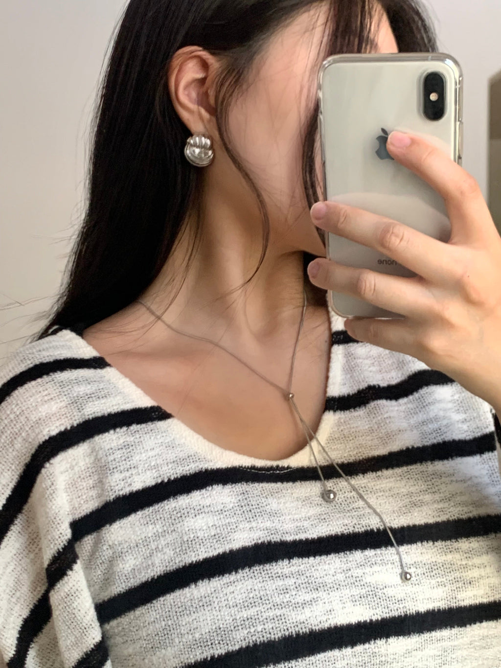 La Flaneuse silver twisted stud earrings worn by a woman in a striped top, reflecting a modern and polished style.
