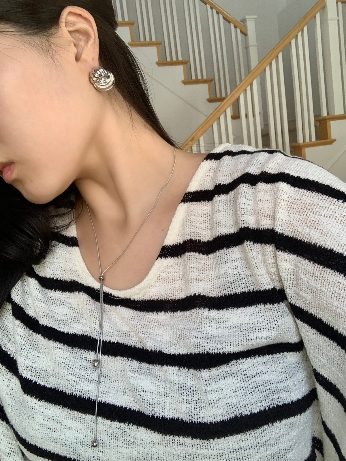 La Flaneuse polished silver twisted earrings worn by a woman in a striped top